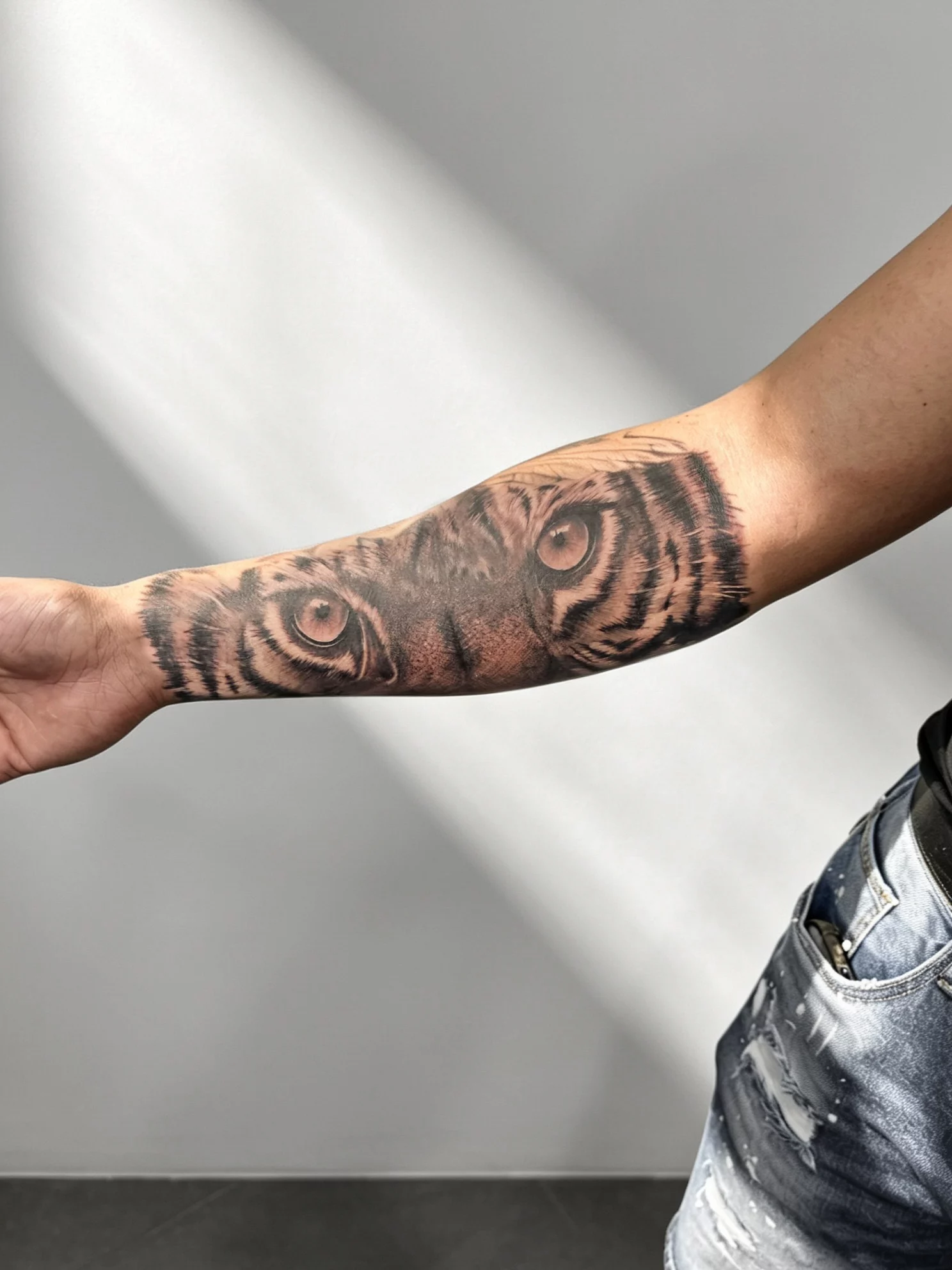 Tatouage réaliste noir et gris des yeux d’un tigre sur l’avant-bras